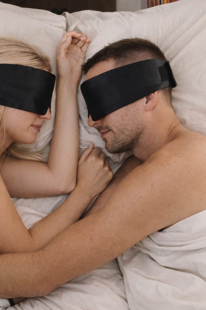 Par som sover vendt mot hverandre med svarte Sovemaske Pro i silke for rolig søvn uten lysforstyrrelser