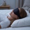 Kvinne sover på siden med svart 3D sovemaske som hviler på kinnbeina